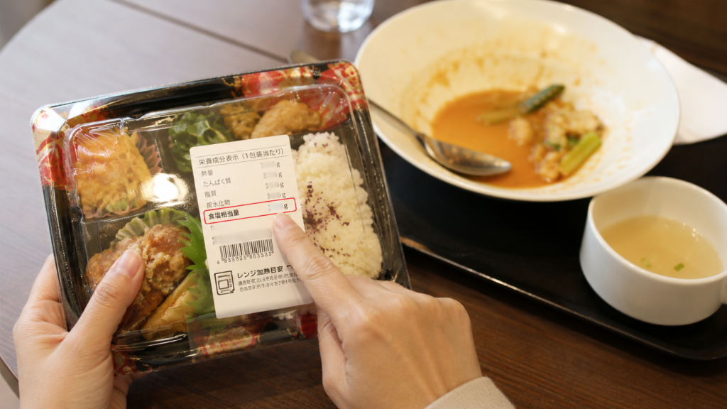 コンビニ弁当の栄養成分表示で食塩相当量を確認する様子